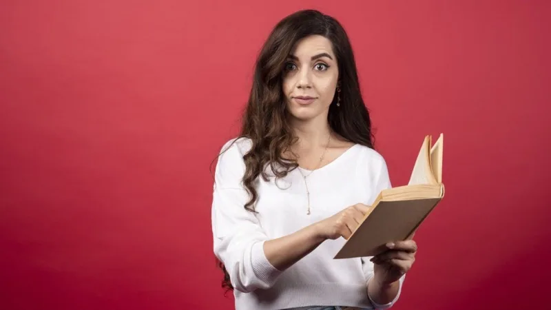 Woman reading a book against a bold red background