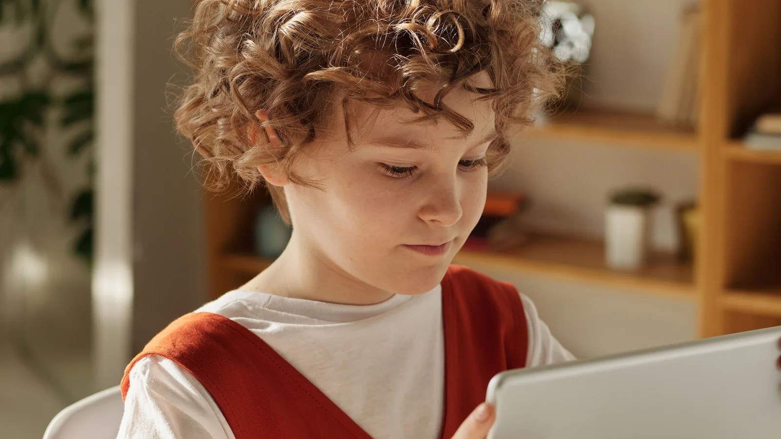 A young child reading a picture book on a tablet at a table