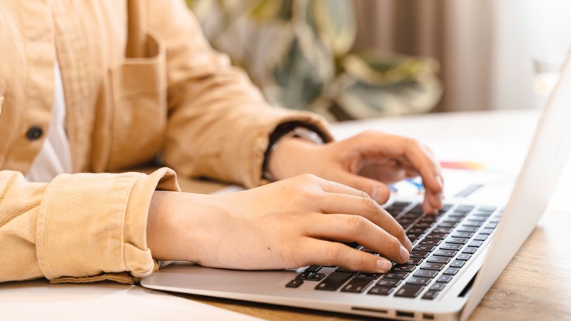 Hands typing on a laptop, representing preparing a manuscript before formatting