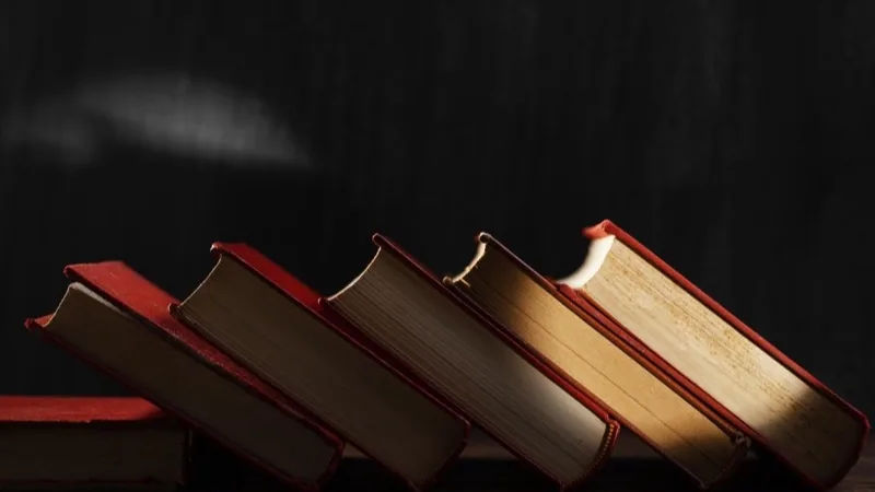 Arrangement of old hardcover books lit by warm light