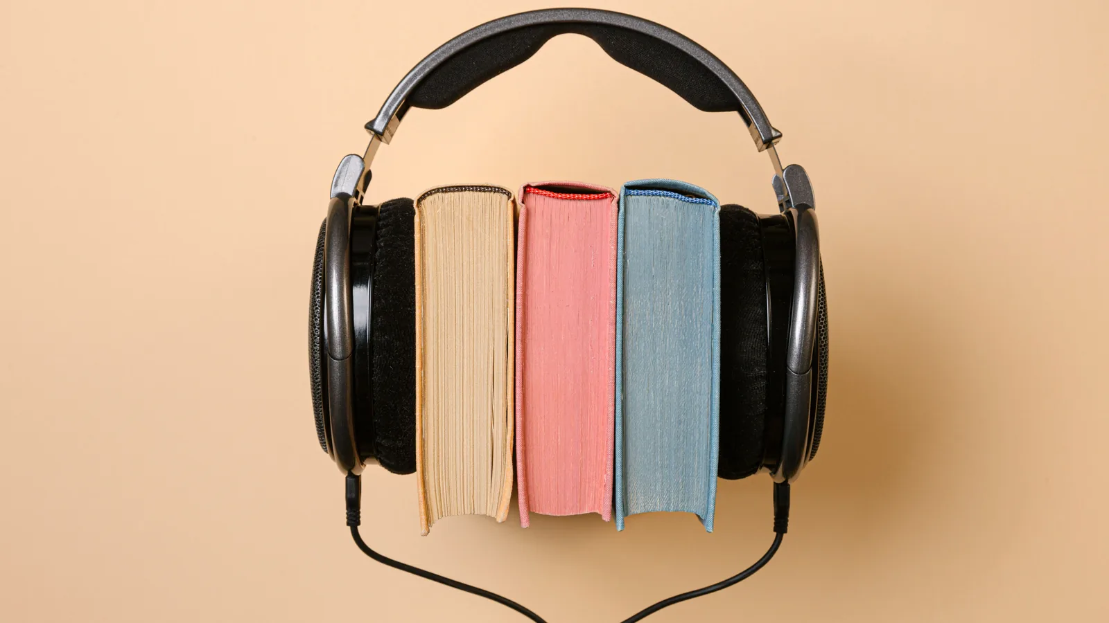 Headphones wrapped around three colorful books, representing a print, ebook and audiobook launch